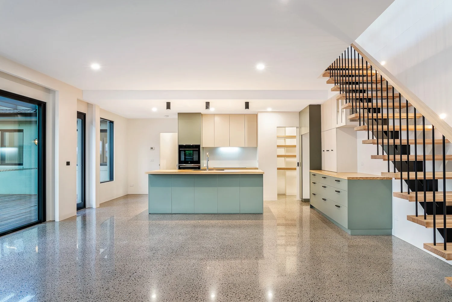 Open-plan kitchen and living with sage island, timber staircase and polished concrete floor, Colin Street Bentleigh East — Eco Building Design