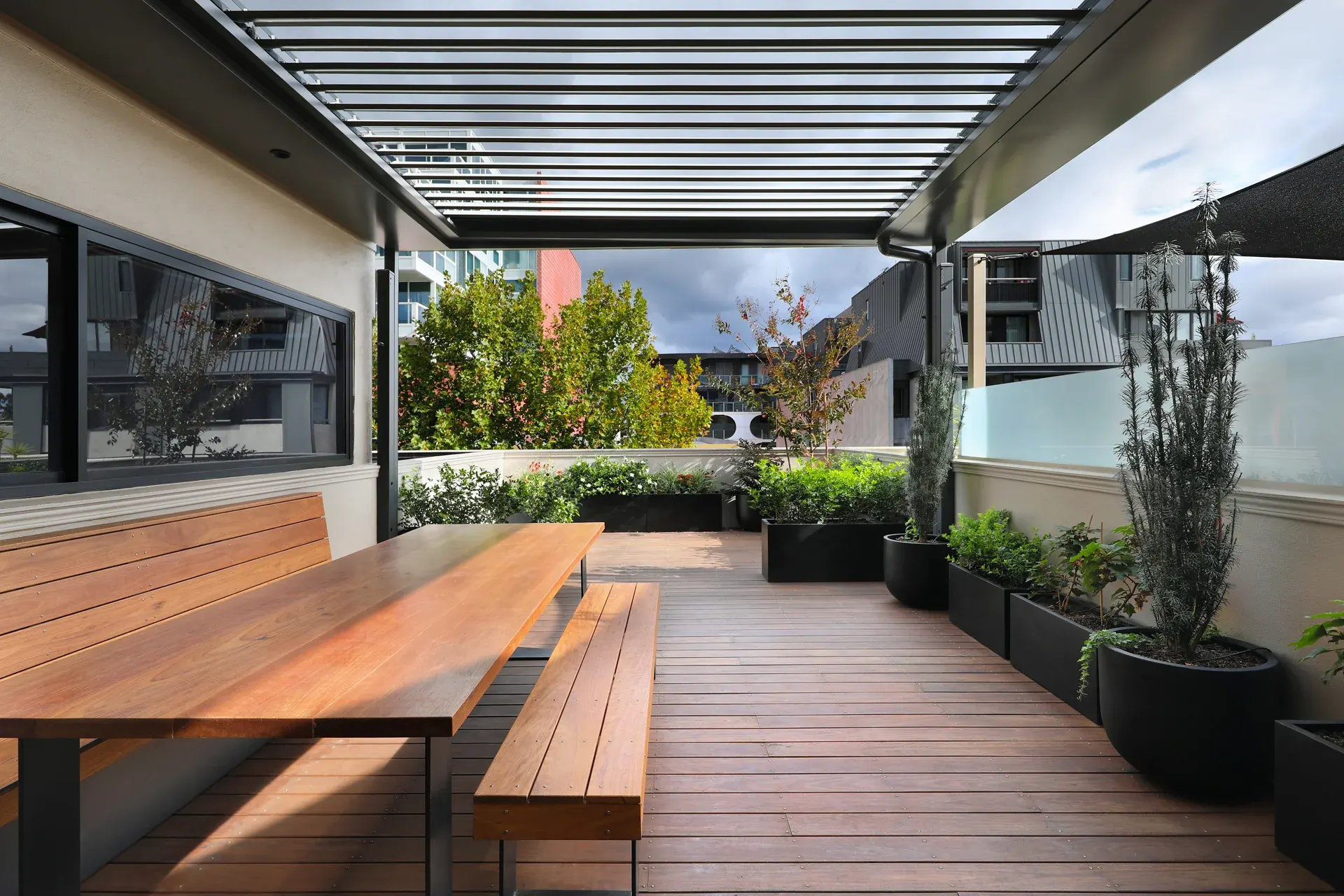 Rooftop terrace with timber dining setting and louvre pergola, George Street Fitzroy — Eco Building Design