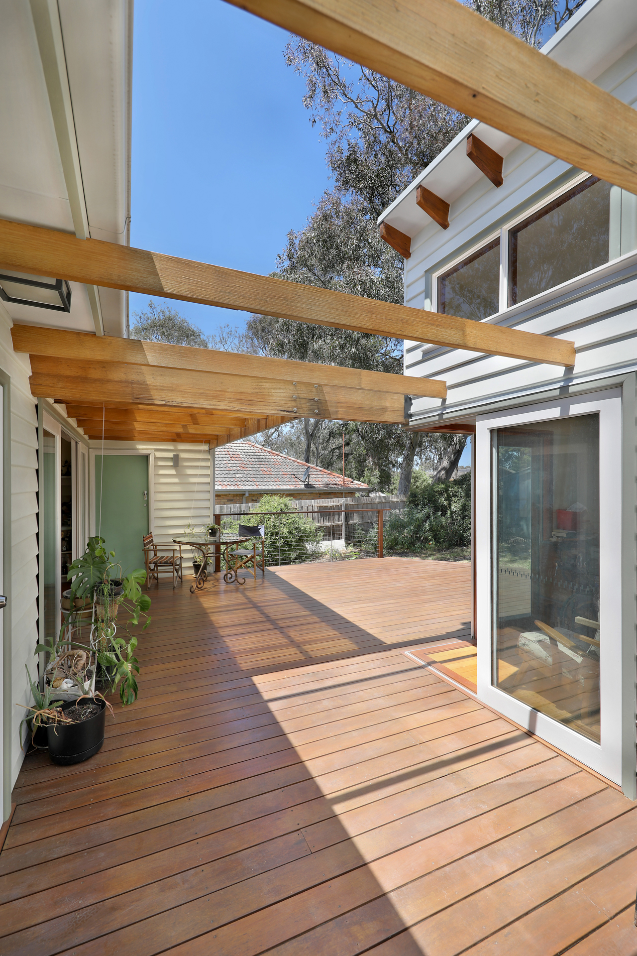 Interior view of covered timber deck framed by tall pergola beams, Joynt Street Macleod — Eco Building Design