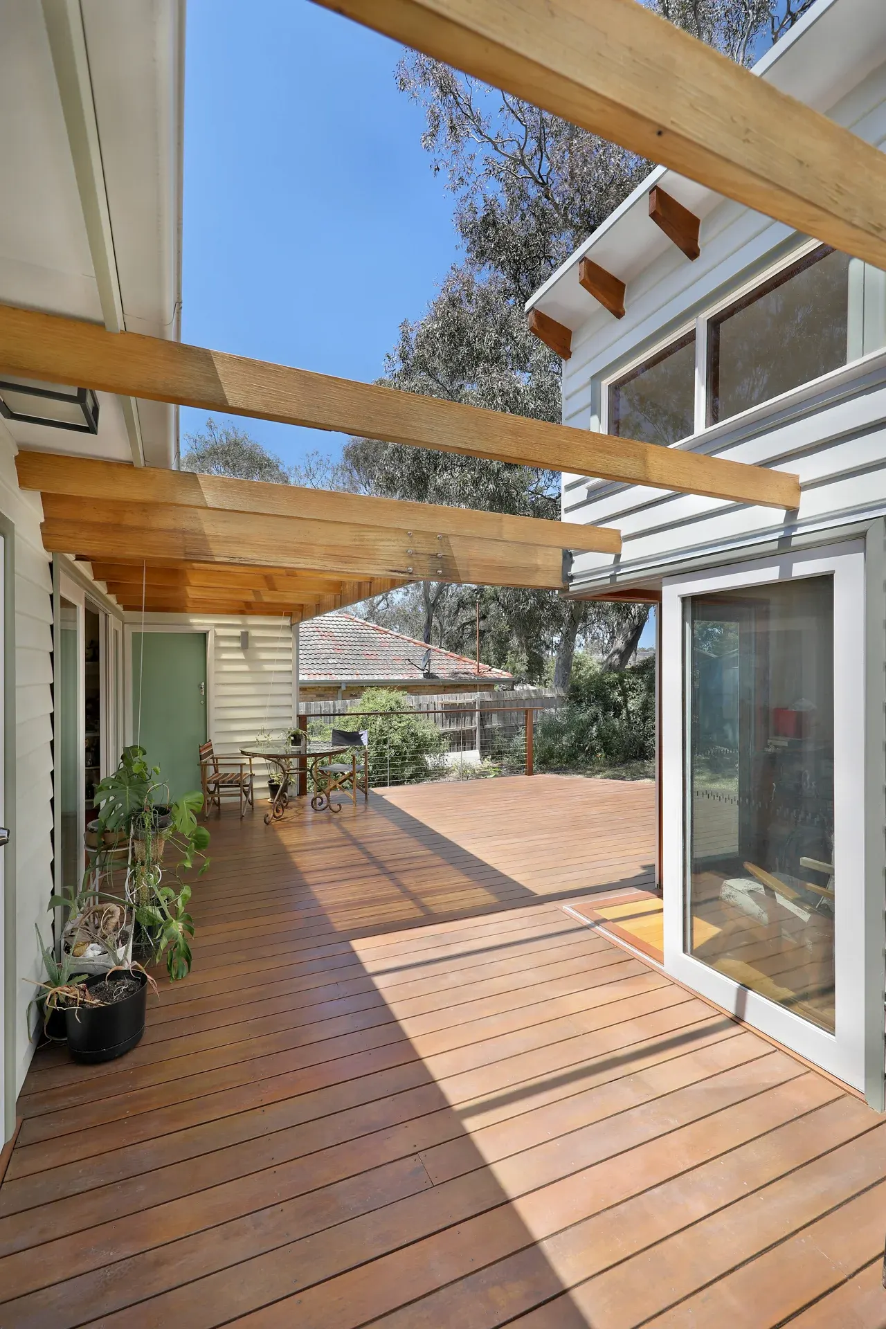 Interior view of covered timber deck framed by tall pergola beams, Joynt Street Macleod — Eco Building Design